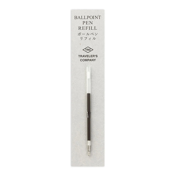 A ballpoint pen refill by Traveler's Company, shown in its original light gray cardboard packaging. The refill features a white upper barrel, a black central grip, and a silver metal tip.